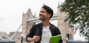 Estudante segurando um caderno verde e com um rosto feliz e sorridente